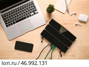 Современный Wi-Fi маршрутизатор с ноутбуком и мобильным телефоном на деревянном фоне. Стоковое фото, фотограф Pixel_shot / Фотобанк Лори