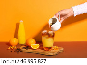 Женщина готовит вкусный апельсиновый эспрессо на цветном фоне. Стоковое фото, фотограф Pixel_shot / Фотобанк Лори