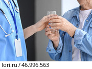 Женщина-сиделка подает старшей женщине стакан воды в комнате, крупным планом. Стоковое фото, фотограф Pixel_shot / Фотобанк Лори