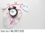 Будильник с рождественскими леденцами, очками и конфетти на белом фоне. Стоковое фото, фотограф Pixel_shot / Фотобанк Лори