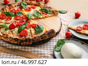 Доска с вкусной пиццей Маргарита и моцареллой на столе. Стоковое фото, фотограф Pixel_shot / Фотобанк Лори