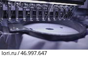 Close up of industrial loom creating embroidery on white fabric. Стоковое фото, фотограф David Kashakhi / Фотобанк Лори