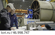 Workers with drawings on factory floor with machines. Стоковое фото, фотограф David Kashakhi / Фотобанк Лори