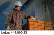 Uniformed worker makes brickwork inside house. Стоковое фото, фотограф David Kashakhi / Фотобанк Лори