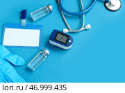 Пульсоксиметр, стетоскоп, значок, ампулы и медицинские перчатки на синем фоне. Стоковое фото, фотограф Pixel_shot / Фотобанк Лори
