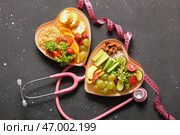 Тарелки с свежими здоровыми продуктами, стетоскоп и измерительная лента на темном фоне. Концепция диеты. Стоковое фото, фотограф Pixel_shot / Фотобанк Лори