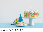 Стойте с вкусным днем рождения тортом, вечеринкой конусами и белковым кремом на цветном фоне. Стоковое фото, фотограф Pixel_shot / Фотобанк Лори