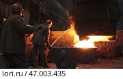 Workers Skillfully Handling Molten Metal in a Busy Foundry Environment with Safety Gear. Стоковое фото, фотограф David Kashakhi / Фотобанк Лори