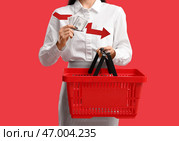 Молодая женщина с корзиной для покупок, деньгами и стрелкой на красном фоне, крупным планом. Концепция повышения цен. Стоковое фото, фотограф Pixel_shot / Фотобанк Лори