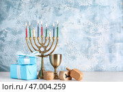 Композиция к Хануке с менорой, кубком, крутизной и подарочными коробками на фоне голубого гранжа. Стоковое фото, фотограф Pixel_shot / Фотобанк Лори