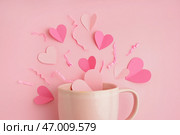 Чашка с сердечками и изрезанной бумагой на розовом фоне. Празднование Дня святого Валентина. Стоковое фото, фотограф Pixel_shot / Фотобанк Лори