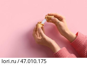 Женские руки с разломанным печеньем с предсказанием на розовом фоне. Стоковое фото, фотограф Pixel_shot / Фотобанк Лори