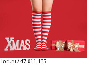 Женщина в рождественских чулках с подарочными коробками и словом XMAS на красном фоне. Стоковое фото, фотограф Pixel_shot / Фотобанк Лори