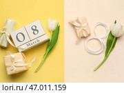 Фигура 8 из ленты с кубическим календарем, подарочными коробками и красивыми тюльпанами на красочном фоне. Празднование Международного женского дня. Стоковое фото, фотограф Pixel_shot / Фотобанк Лори