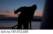 Man cleans up on boat on winter evening at sea. Стоковое фото, фотограф David Kashakhi / Фотобанк Лори