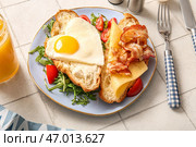 Тарелка с вкусным жареным яйцом, нарезанным круассаном, беконом, помидорами и стакан сокa на светлом фоне плитки, крупным планом. Стоковое фото, фотограф Pixel_shot / Фотобанк Лори