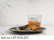 Стакан рома, дольки апельсина и сигара в пепельнице на тарелке на столе на сером фоне. Крупный план. Стоковое фото, фотограф Pixel_shot / Фотобанк Лори
