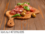 Доска с ломтями вкусного прошутто и оливками на деревянном фоне. Стоковое фото, фотограф Pixel_shot / Фотобанк Лори