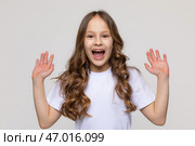 Photo of happy astonished girl in white t-shirt, open mouth, raise show two arm, enjoy satisfied sale or good news isolated on white background. Стоковое фото, фотограф Ирина Михайличенко / Фотобанк Лори