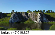 A picturesque scenic rock formation located near a tranquil river beneath a clear blue sky. Стоковое фото, фотограф David Kashakhi / Фотобанк Лори