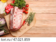 Пергамент с сырыми свиными ребрышками, специями и овощами на деревянном фоне. Стоковое фото, фотограф Pixel_shot / Фотобанк Лори