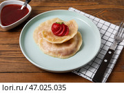 Тарелка с вкусными клубничными клецками и соусом на деревянном фоне. Стоковое фото, фотограф Pixel_shot / Фотобанк Лори