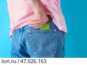 Мужчина кладет презерватив в карман джинсов на цветном фоне, крупным планом. Стоковое фото, фотограф Pixel_shot / Фотобанк Лори