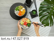 Женщина ест вкусный рис тыкать миской на деревянном фоне. Стоковое фото, фотограф Pixel_shot / Фотобанк Лори