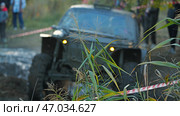 On a background of green grass, an off-road vehicle is seen ruggedly driving along a muddy track during a competition. Extreme mud racing. Стоковое фото, фотограф Воловодов Владимир / Фотобанк Лори