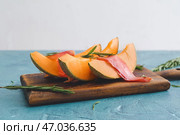 Доска с вкусной дыней и прошутто на цветном столе. Стоковое фото, фотограф Pixel_shot / Фотобанк Лори
