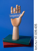 Книги и деревянная рука, держащая бумагу со словом IMPEACH на цветном фоне. Стоковое фото, фотограф Pixel_shot / Фотобанк Лори