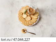 Тарелка с вкусными крекерами и баночка с арахисовым маслом на светлом фоне. Стоковое фото, фотограф Pixel_shot / Фотобанк Лори