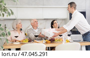 Birthday senior man accepts outright gift and greetings from adult son during family feast. Стоковое фото, фотограф Яков Филимонов / Фотобанк Лори