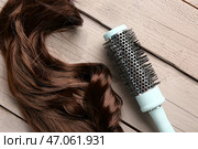 Завитые коричневые волосы с круглой щеткой на сером деревянном фоне, крупным планом. Стоковое фото, фотограф Pixel_shot / Фотобанк Лори