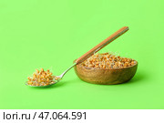 Чашка и ложка с пророщенной пшеницей на светло-зеленом фоне. Стоковое фото, фотограф Pixel_shot / Фотобанк Лори