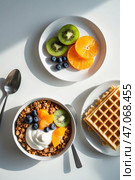 Delicious breakfast featuring yogurt, granola, fresh fruits, and waffles on a sunny morning table. Стоковое AI-изображение, AI-художник Сергей Толмачёв / Фотобанк Лори