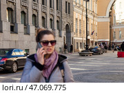 Young Woman Talks on a Phone in an Urban Setting With Historic Architecture in the Background. Стоковое фото, фотограф Aleksandr Golubev / Фотобанк Лори
