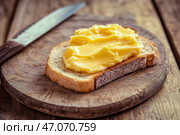 Slice of wholemeal bread with butter curl. Buttering toast. Yellow butter scattered on a piece of bread. Bread with toasting and spreading butter. Generous spread of butter on a rustic bread slice. Стоковое AI-изображение, AI-художник Марина Демидюк / Фотобанк Лори