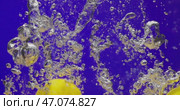 Throwing lemons into water on blue background. Making lemon juice. Стоковое видео, видеограф Владимир Ковальчук / Фотобанк Лори