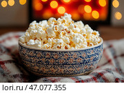Warm buttered popcorn in a charming bowl beside a cozy blanket. попкорн. Стоковое AI-изображение, AI-художник Katsiaryna Repich / Фотобанк Лори