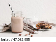 Банка с крышкой, наполненная сладким шоколадным молоком, с вкусным печеньем и какао-бобами на белом фоне. Стоковое фото, фотограф Pixel_shot / Фотобанк Лори