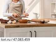 Женщина просеивает муку в миску для приготовления теста на кухонном столе. Стоковое фото, фотограф Pixel_shot / Фотобанк Лори