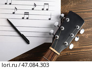 Нотные листы, ручка и гитара на деревянном фоне, крупный план. Стоковое фото, фотограф Pixel_shot / Фотобанк Лори
