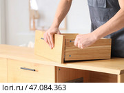 Мужчина-плотник закручивает винт в деревянном ящике с помощью отвертки. Стоковое фото, фотограф Pixel_shot / Фотобанк Лори