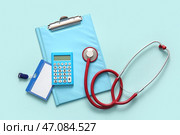 Клипборд, калькулятор и стетоскоп на светло-голубом фоне. Концепция медицинского страхования. Стоковое фото, фотограф Pixel_shot / Фотобанк Лори