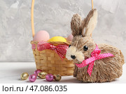 Игрушечный пасхальный кролик и корзина с крашеными яйцами на столе на сером фоне. Стоковое фото, фотограф Pixel_shot / Фотобанк Лори