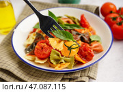 Вилка с вкусной пастой фарфалле, томатами и базиликом на светлом фоне, крупным планом. Стоковое фото, фотограф Pixel_shot / Фотобанк Лори