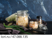 Стеклянная банка с домашней квашеной капустой, салфетка и зеленый лук на столе на фоне голубой стены. Крупный план. Стоковое фото, фотограф Pixel_shot / Фотобанк Лори