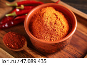 Миска и ложка с красным чилийским порошком и перцами на деревянном фоне, крупный план. Стоковое фото, фотограф Pixel_shot / Фотобанк Лори