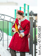 Юноша в старорусской одежде с балалайкой. Празднование Масленицы на территории Кафедрального собора в честь Преображения Господня. Бердск, Новосибирская область, Западная Сибирь, Россия. Редакционное фото, фотограф Евгений Мухортов / Фотобанк Лори